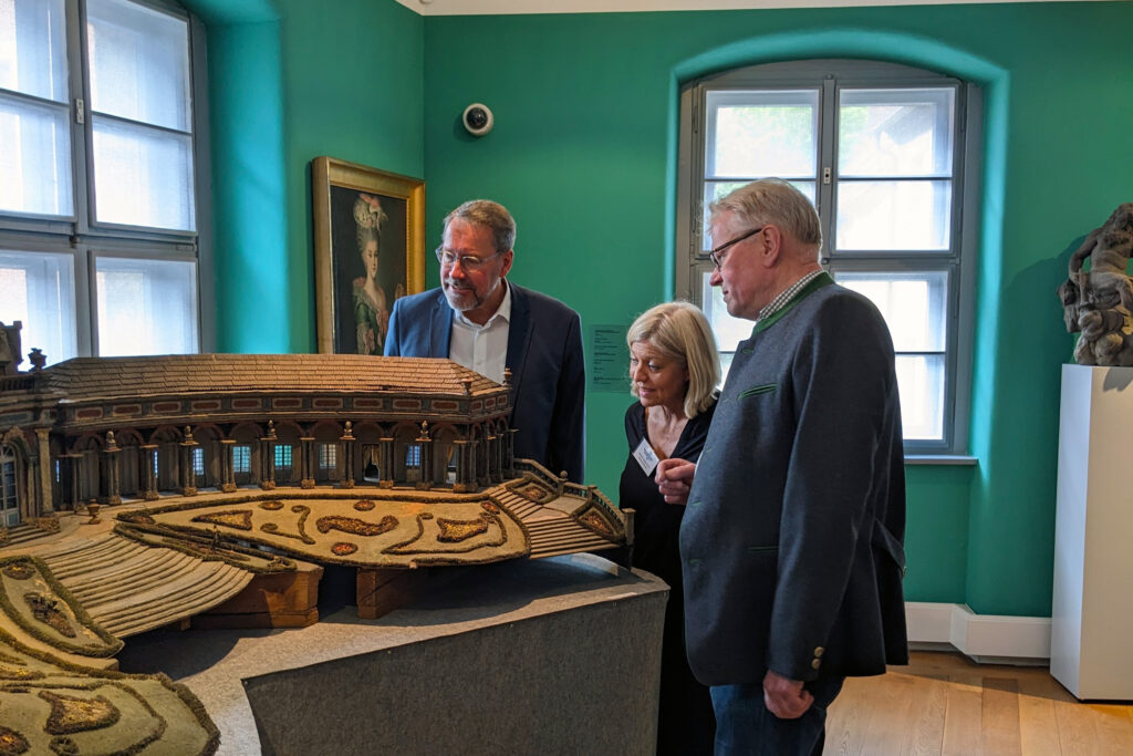 Stadtrat Dr. Specht, Museumsleiterin Ruppert und OB Ebersberger sehen sich ein Modell des neuen Schlosses der Eremitage bei Bayreuth an.